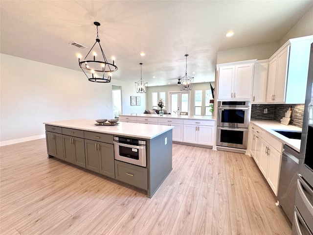 kitchen with decorative light fixtures, white cabinetry, and a center island