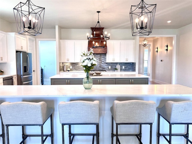 kitchen featuring white cabinets, stainless steel fridge, hanging light fixtures, and a center island