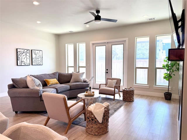 living room featuring ceiling fan, light hardwood / wood-style floors, french doors, and a healthy amount of sunlight