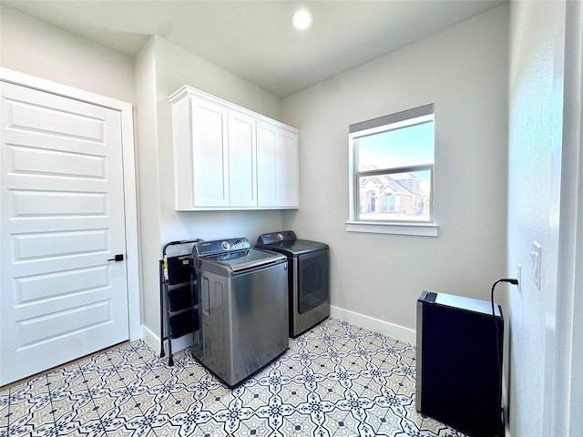 clothes washing area featuring independent washer and dryer and cabinets