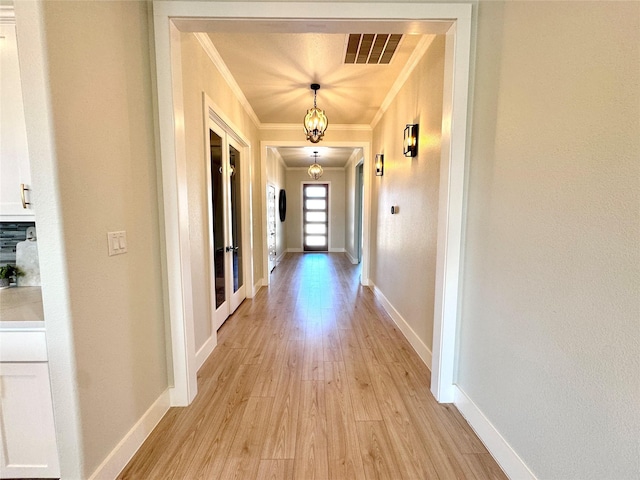 hall with light hardwood / wood-style floors and crown molding