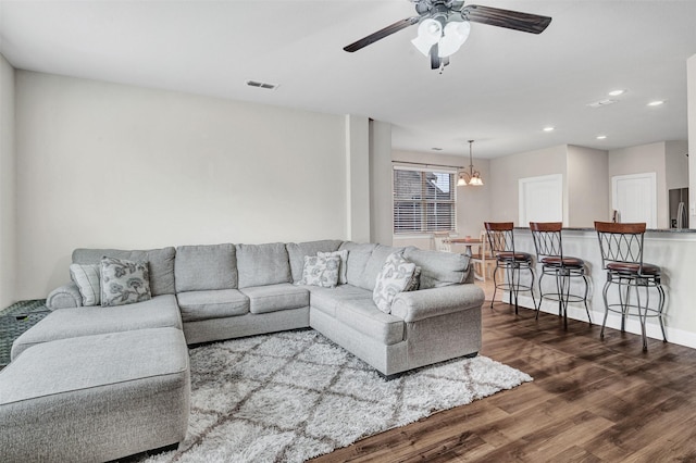 living room featuring ceiling fan with notable chandelier and dark hardwood / wood-style floors