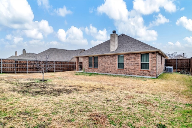 rear view of property featuring central AC and a lawn