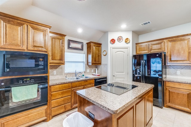 kitchen featuring light tile patterned floors, black appliances, a sink, and a center island