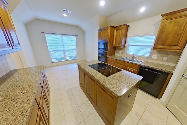 kitchen with a kitchen island, a sink, visible vents, vaulted ceiling, and black appliances