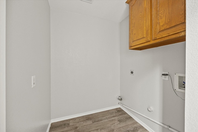 laundry area featuring dark hardwood / wood-style flooring, cabinets, hookup for a gas dryer, washer hookup, and electric dryer hookup