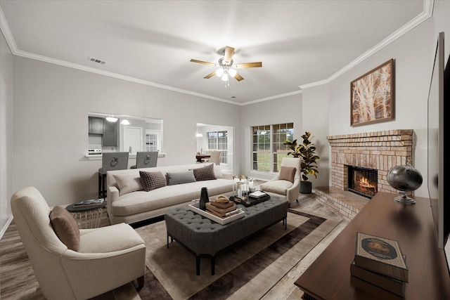 living room featuring hardwood / wood-style floors, crown molding, a brick fireplace, and ceiling fan