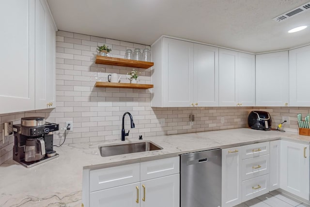 kitchen with stainless steel dishwasher, light stone countertops, sink, and white cabinets