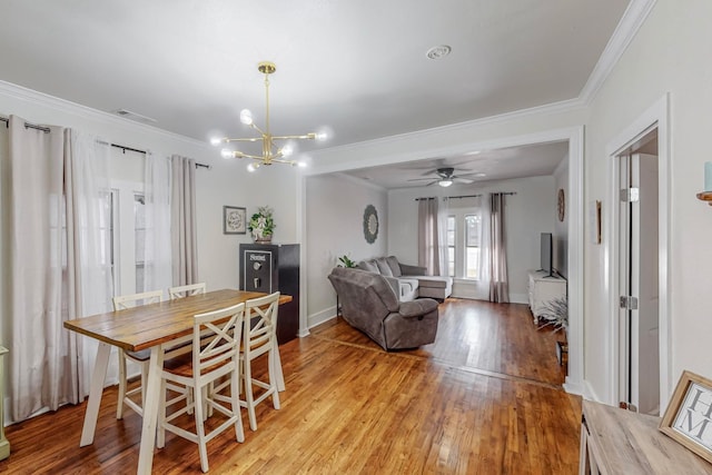 dining space with crown molding, ceiling fan with notable chandelier, and light hardwood / wood-style floors