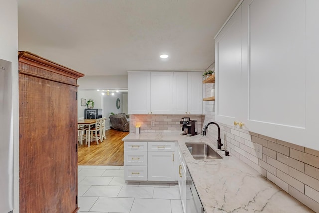 kitchen with sink, dishwasher, white cabinetry, light stone countertops, and decorative backsplash