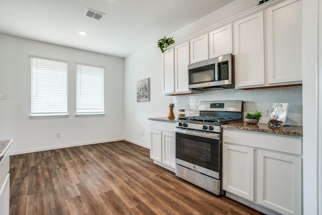 kitchen featuring white cabinetry, tasteful backsplash, dark stone counters, dark hardwood / wood-style flooring, and stainless steel appliances