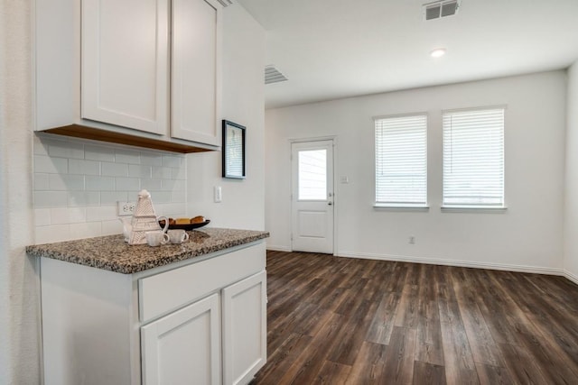 kitchen featuring white cabinetry, backsplash, dark hardwood / wood-style floors, and dark stone counters