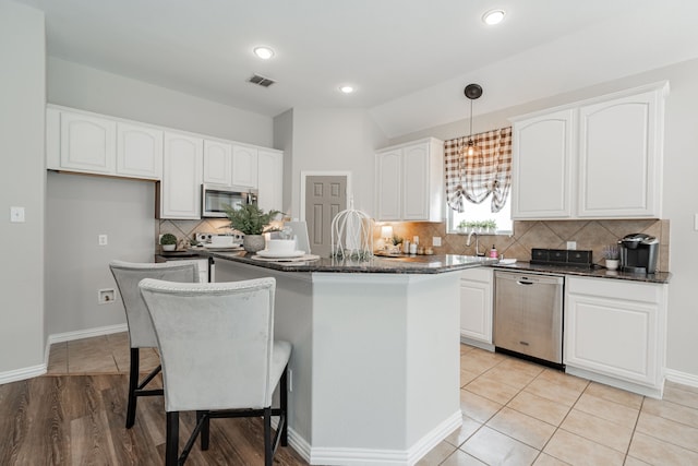 kitchen featuring white cabinetry, a kitchen bar, stainless steel appliances, and a kitchen island