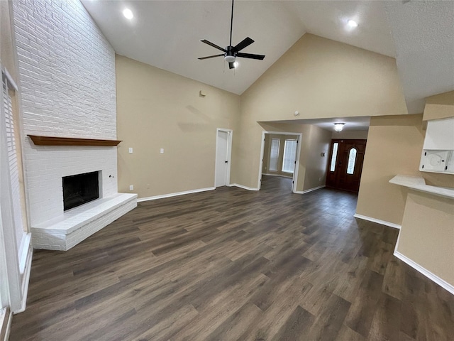 unfurnished living room with dark wood-type flooring, a brick fireplace, ceiling fan, high vaulted ceiling, and baseboards