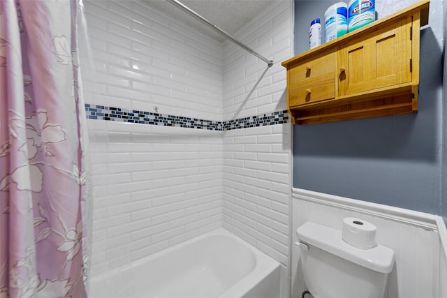 bathroom featuring shower / bath combination with curtain, toilet, and a textured ceiling