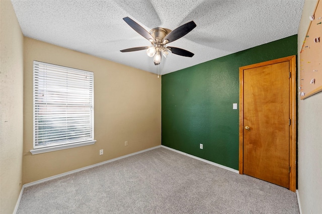 spare room featuring ceiling fan, light colored carpet, and a textured ceiling