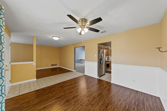 empty room featuring ceiling fan, a textured ceiling, and light hardwood / wood-style floors