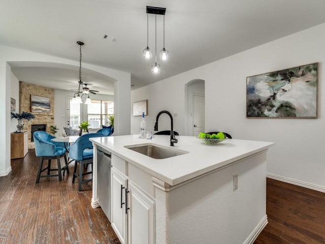 kitchen with sink, a kitchen island with sink, white cabinetry, hanging light fixtures, and stainless steel dishwasher