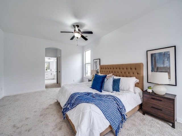 bedroom with light carpet, ensuite bath, and ceiling fan