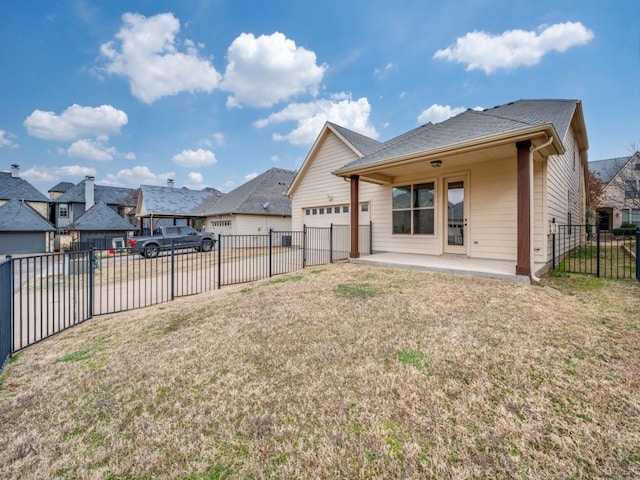 back of property with a garage, a yard, and a patio