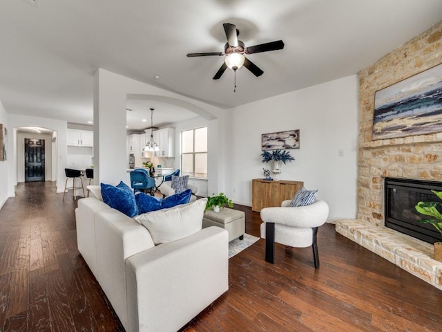 living room with ceiling fan, a fireplace, and dark hardwood / wood-style flooring