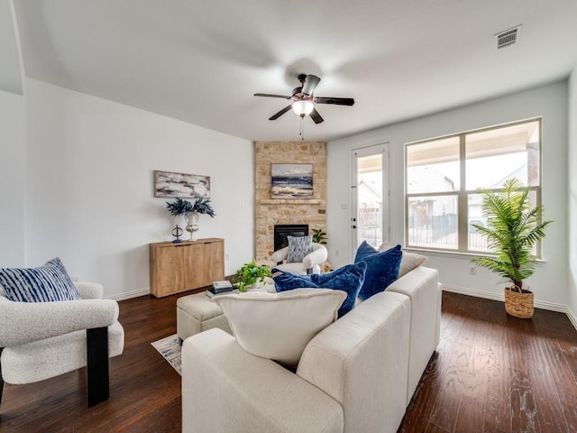 living room featuring dark wood-type flooring, a large fireplace, and ceiling fan