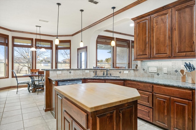 kitchen featuring sink, light stone counters, tasteful backsplash, a center island, and ornamental molding