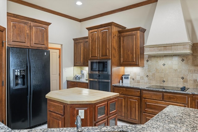 kitchen featuring tasteful backsplash, premium range hood, a kitchen island, and black appliances