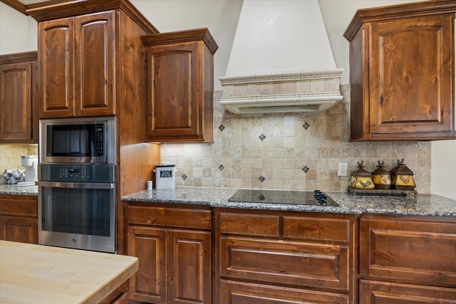 kitchen with decorative backsplash, custom exhaust hood, dark stone counters, and appliances with stainless steel finishes