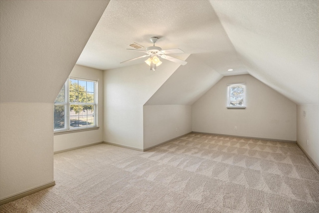 bonus room with lofted ceiling, a textured ceiling, light carpet, and a wealth of natural light