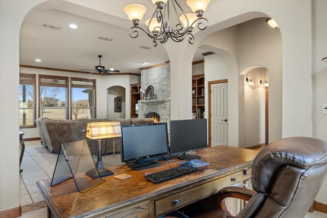 office area featuring light tile patterned flooring, ceiling fan with notable chandelier, a fireplace, crown molding, and built in shelves