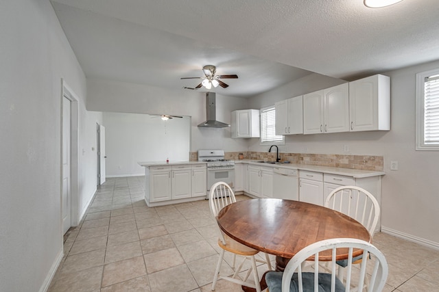 kitchen with white cabinetry, sink, light tile patterned floors, white appliances, and wall chimney exhaust hood