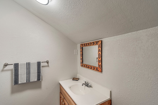 bathroom with vanity, lofted ceiling, and a textured ceiling