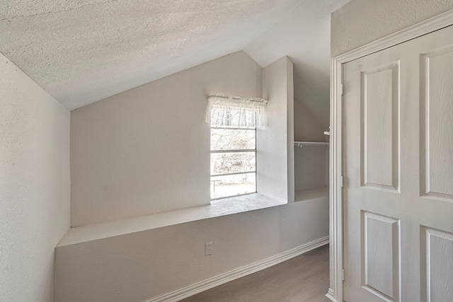 bonus room featuring wood-type flooring, lofted ceiling, and a textured ceiling