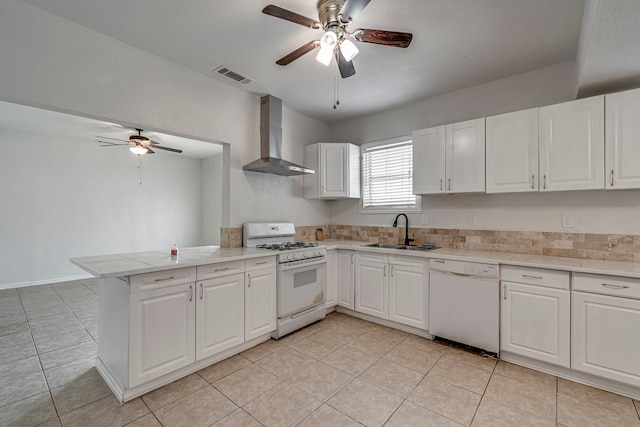 kitchen with sink, kitchen peninsula, white appliances, wall chimney range hood, and white cabinets