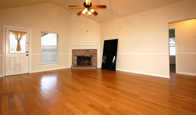 unfurnished living room featuring hardwood / wood-style floors, high vaulted ceiling, a brick fireplace, and ceiling fan