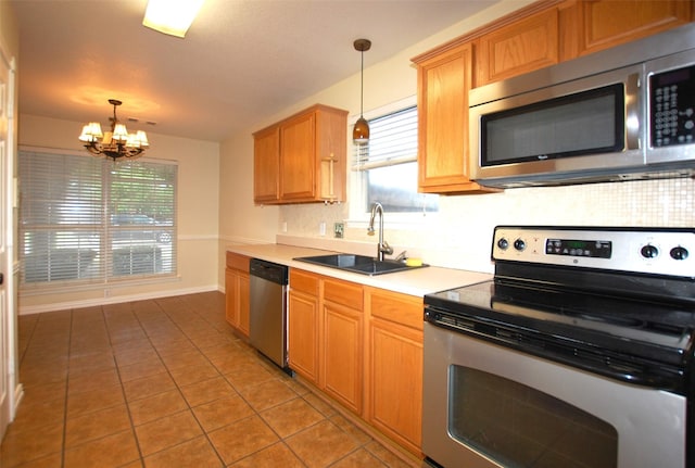 kitchen featuring appliances with stainless steel finishes, sink, light tile patterned floors, and decorative light fixtures