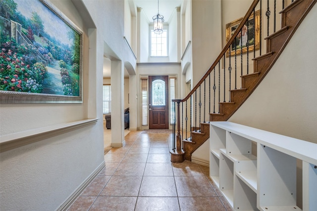 entryway with a high ceiling, light tile patterned flooring, and a notable chandelier