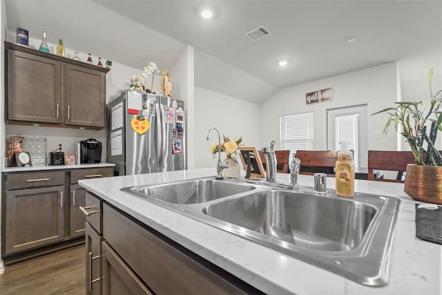 kitchen featuring sink, stainless steel refrigerator, dark brown cabinets, dark hardwood / wood-style flooring, and vaulted ceiling