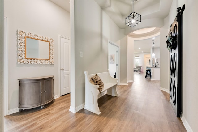 corridor with light hardwood / wood-style flooring, a barn door, and a high ceiling