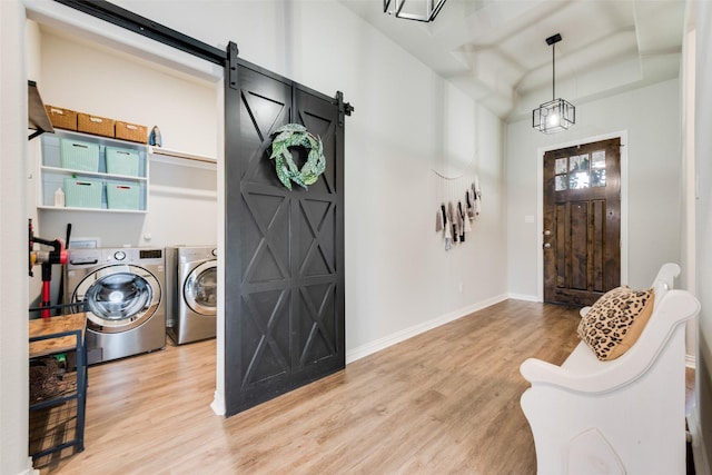 washroom with a barn door, independent washer and dryer, and light hardwood / wood-style flooring