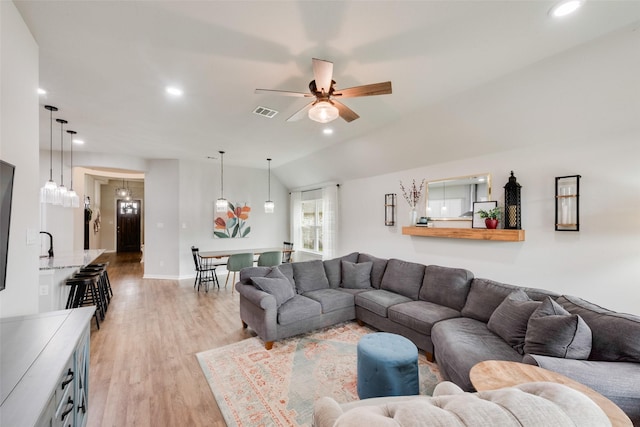 living room with ceiling fan, lofted ceiling, and light wood-type flooring