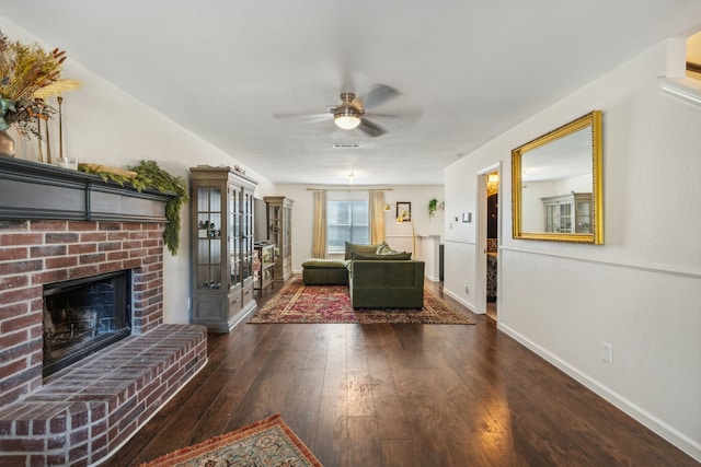 unfurnished living room with ceiling fan, a brick fireplace, and dark hardwood / wood-style flooring