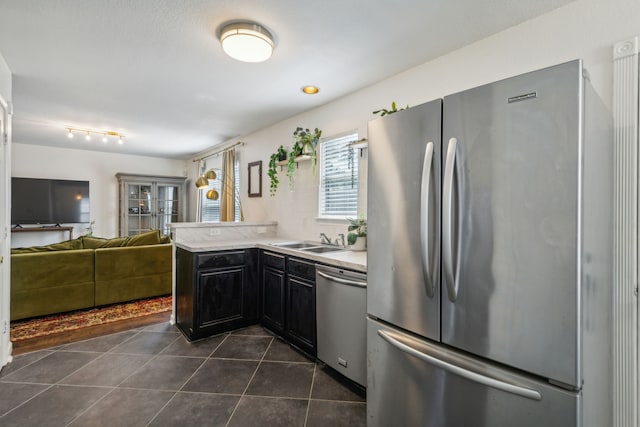 kitchen featuring appliances with stainless steel finishes, dark tile patterned flooring, sink, and kitchen peninsula