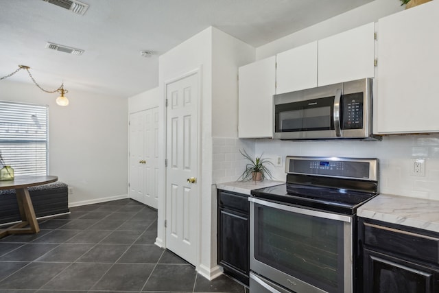 kitchen featuring white cabinetry, stainless steel appliances, tasteful backsplash, and dark tile patterned floors