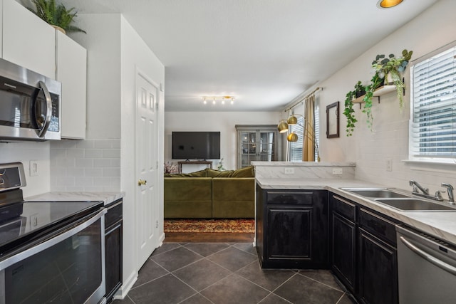 kitchen with sink, dark tile patterned floors, backsplash, stainless steel appliances, and white cabinets