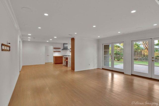 unfurnished living room with crown molding, light hardwood / wood-style floors, and french doors