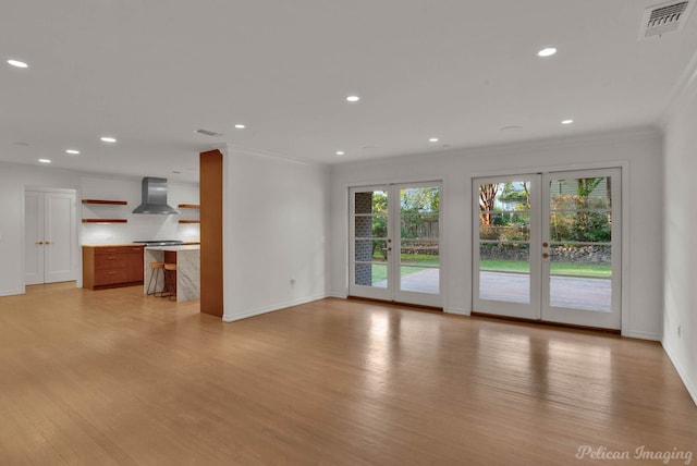 unfurnished living room with crown molding, light hardwood / wood-style flooring, and french doors