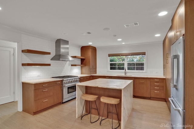 kitchen featuring wall chimney exhaust hood, sink, crown molding, a center island, and high quality appliances