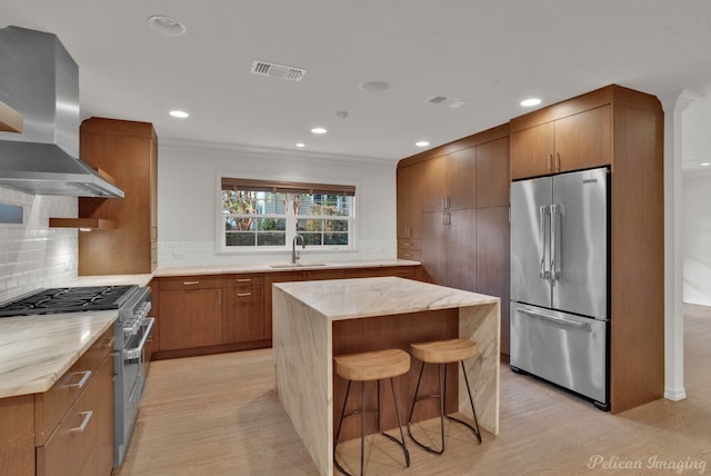 kitchen featuring high quality appliances, a kitchen breakfast bar, a kitchen island, and wall chimney range hood